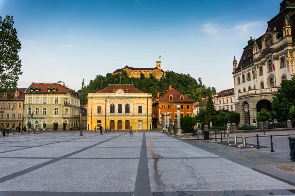 Scenic view of Ljubljana's central square with historical architecture and Ljubljana Castle in the background.
