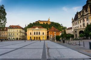 Scenic view of Ljubljana's central square with historical architecture and Ljubljana Castle in the background.